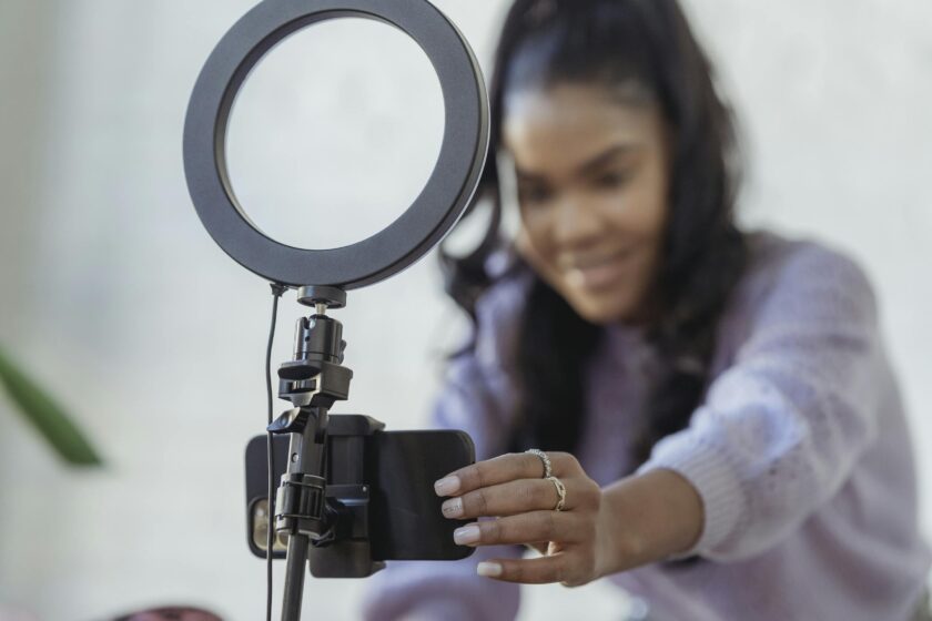 African American female smiling while setting up camera of smartphone attached to tripod